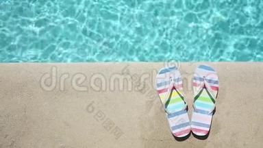 蓝色游泳池附近的彩色夏季凉鞋